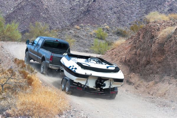 black truck towing a white boat up a hill